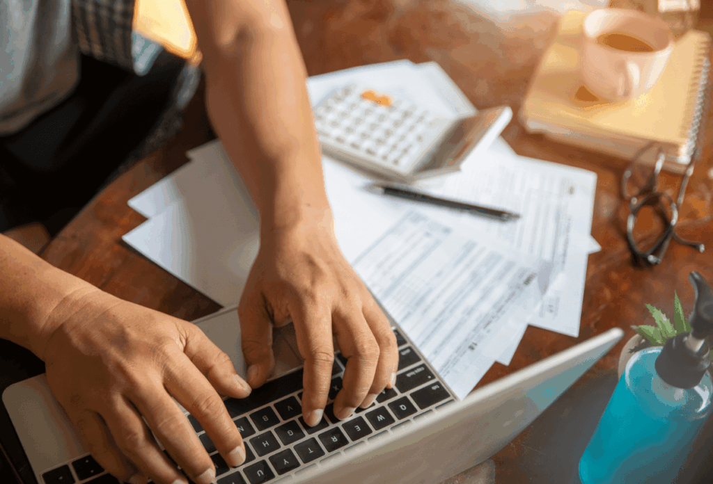 photo of someone using a laptop and calculator to create a marketing budget