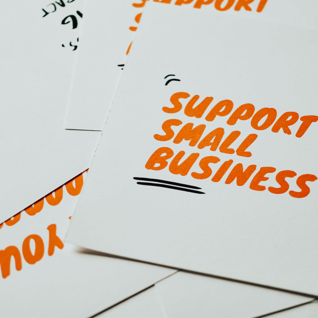Cards are piled on a table with "Support Small Business" written on them in orange text.